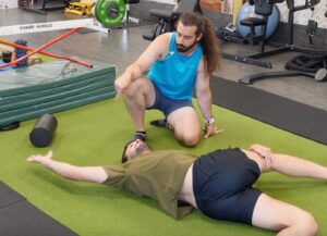 Rene on his back, right hip stacked ontop of the left with legs in a 4 position.  He is trying to get both shoulders onto the ground and is sweeping his right arm overhead as a bjj arm bar mobility exercise